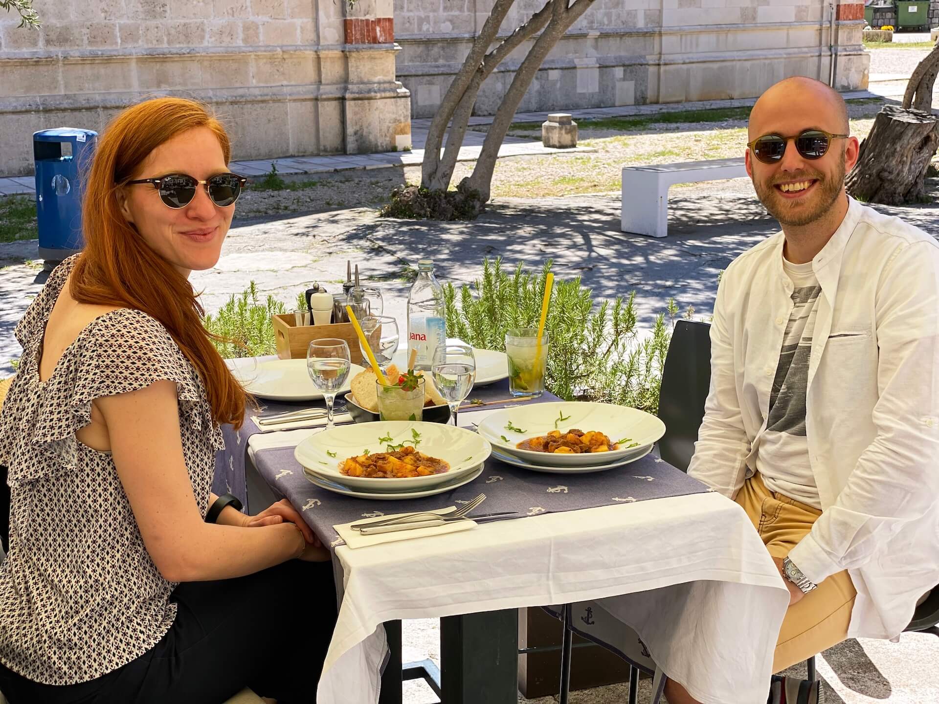 Two guests dining outdoors at a table set with anchor-print linens.