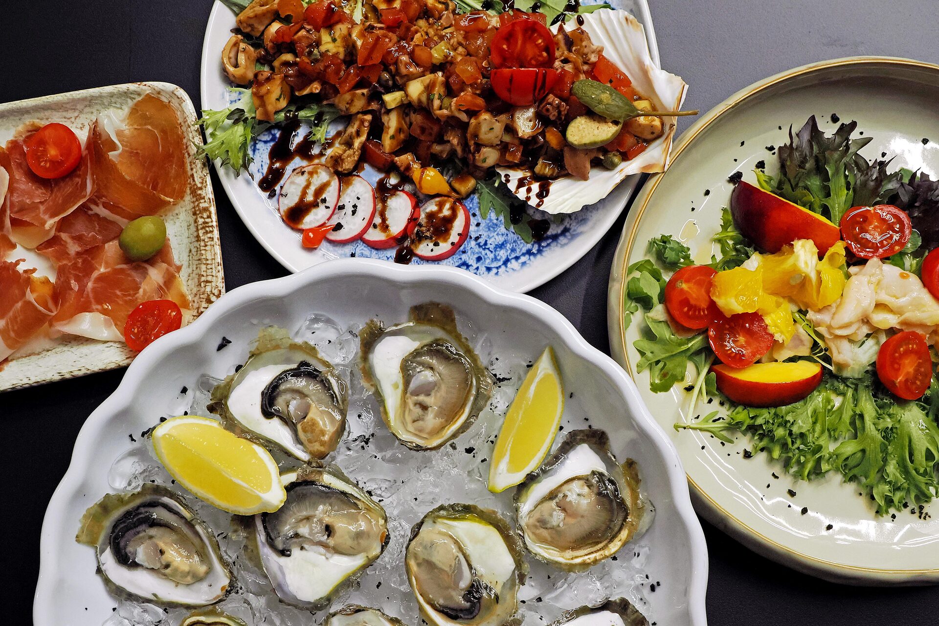 Fresh Mali Ston oysters on ice with lemon, alongside prosciutto, octopus salad and a mixed salad.