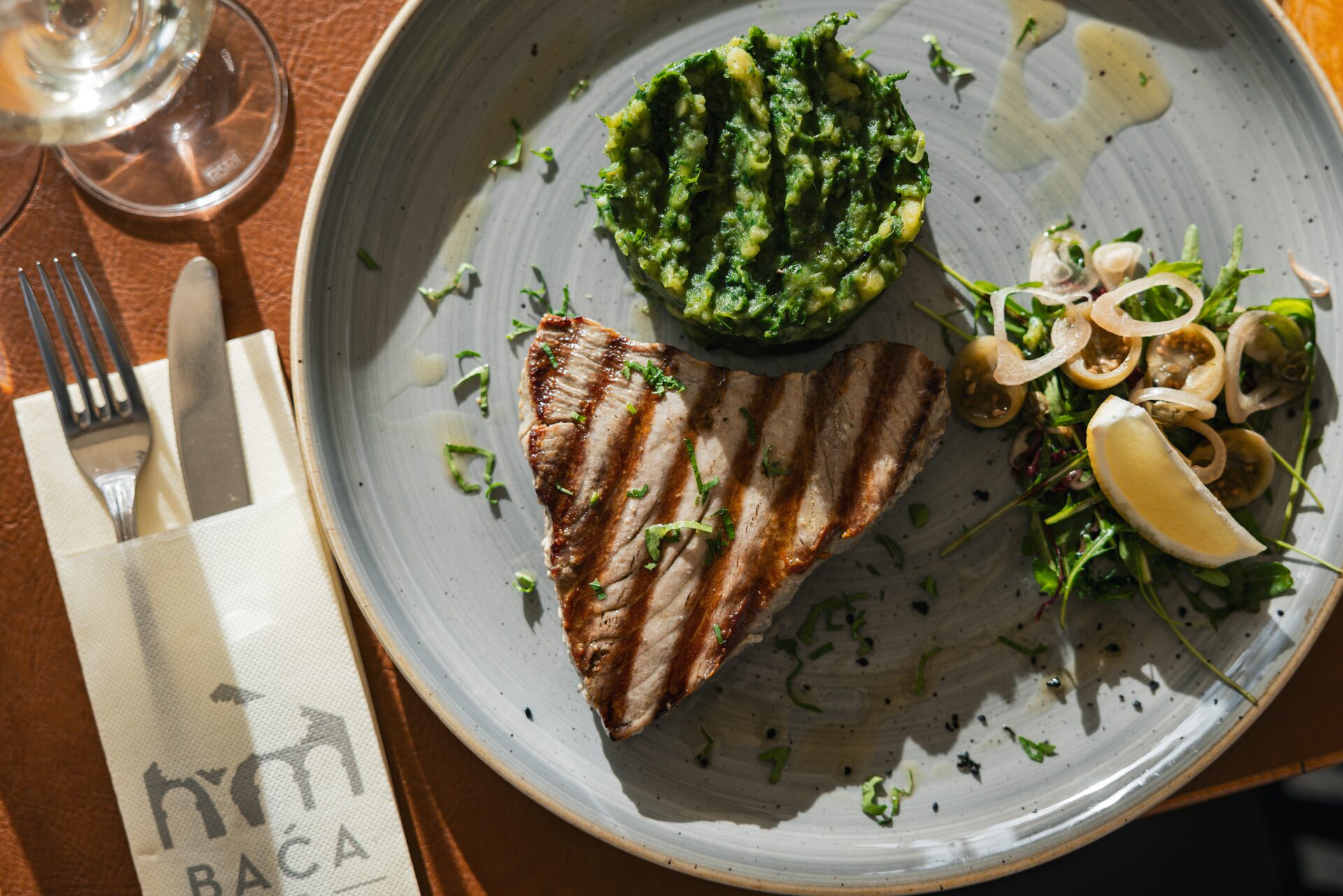 Grilled tuna steak with Swiss chard, squid and a wedge of lemon.