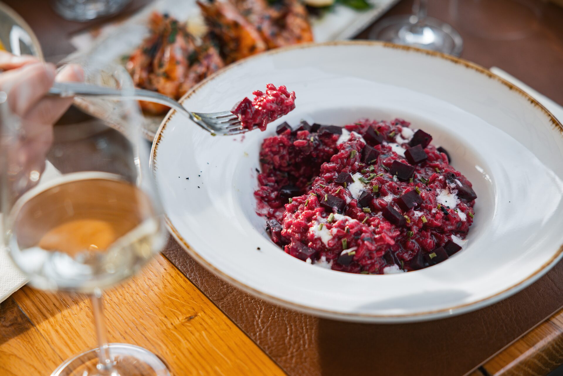 Beetroot risotto with crumbled cheese, served with a glass of white wine.